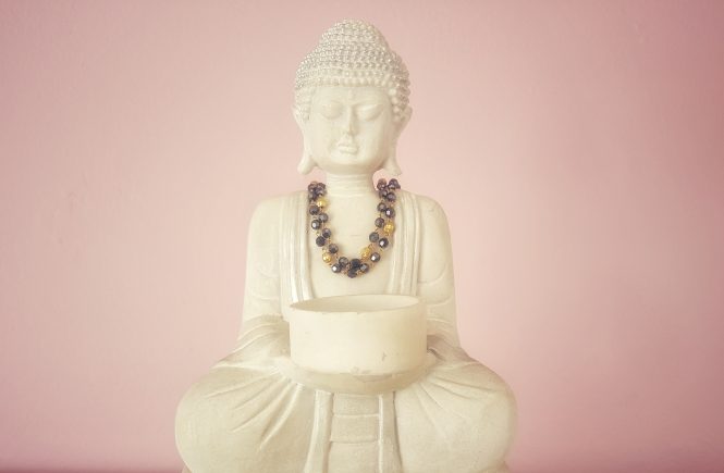 Buddha statue with necklace and pink background
